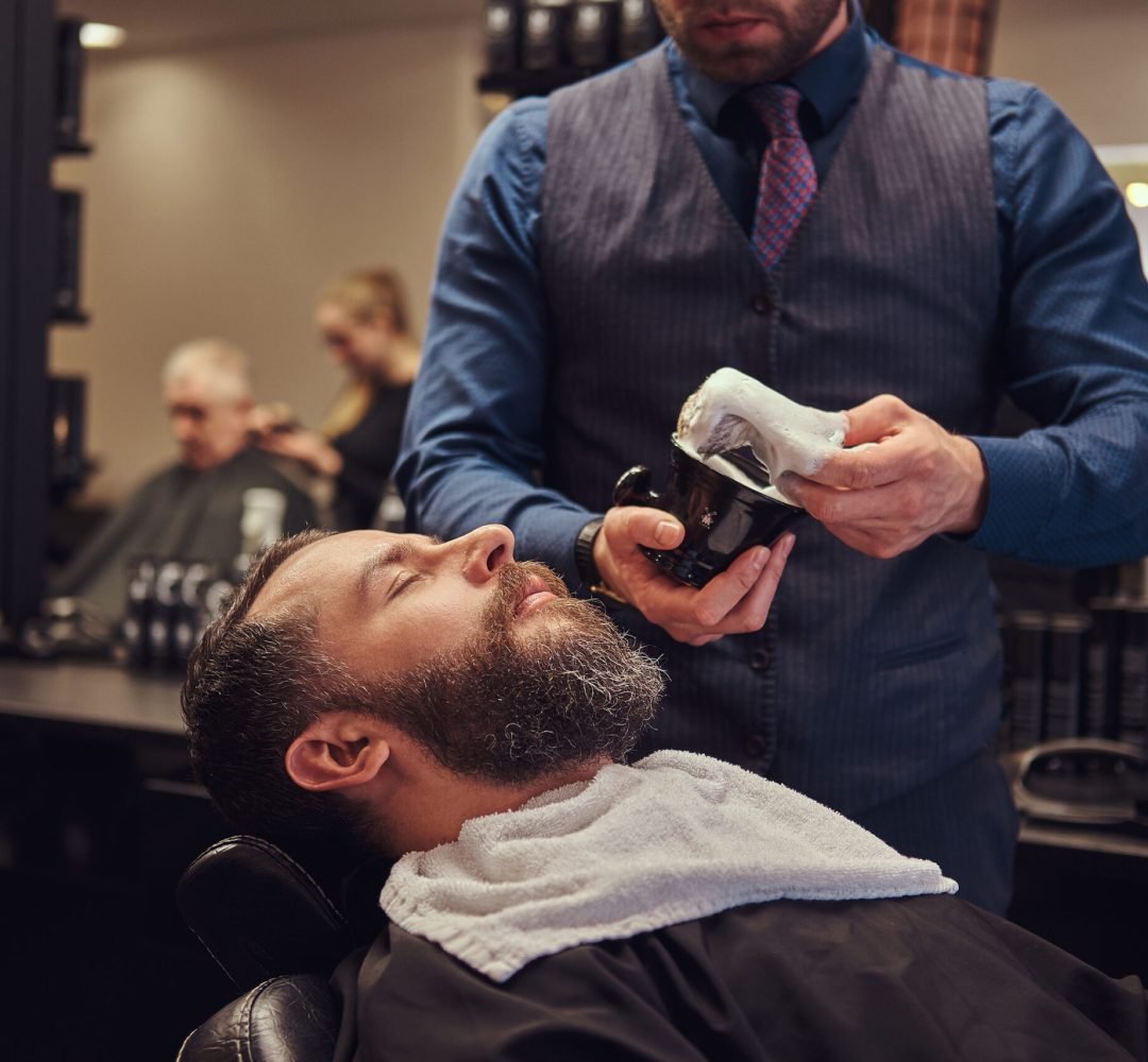 Master hairdresser prepares the face for shaving, deals foam.